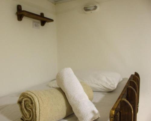 a bed with towels and a cross on a wall at Artetude Hostel Cultural in Barra de Guaratiba