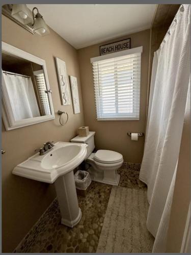 a bathroom with a sink and a toilet and a mirror at Second Floor Oceanfront Unit in Brant Beach