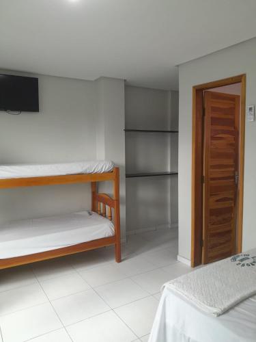 a room with two bunk beds and a television at Hotel Algaroba Anexo in Bom Jesus da Lapa