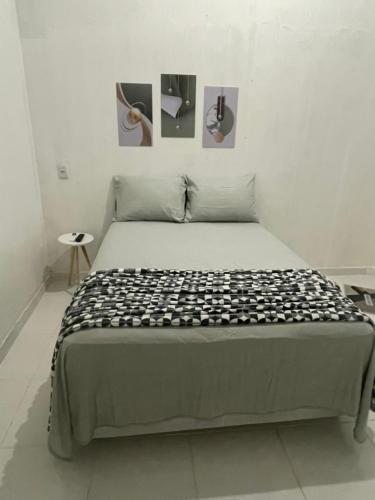 a bed in a room with two pictures on the wall at Suítes JK in Paragominas