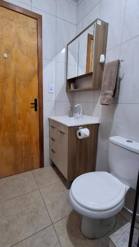 a bathroom with a toilet and a sink and a mirror at Casa com piscina aquecida, 3 quartos e 3 camas extras in Capão da Canoa