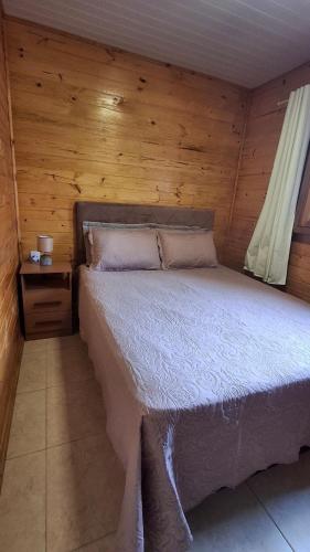 a bedroom with a bed and a wooden wall at Casa com piscina aquecida, 3 quartos e 3 camas extras in Capão da Canoa
