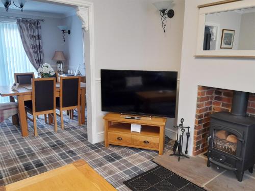 a living room with a fireplace and a flat screen tv at Wheelhouse 21 in Amble