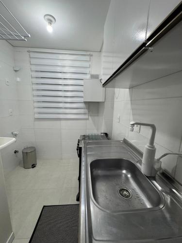 a kitchen with a stainless steel sink and a tub at Refúgio Vila Mar Apto in Imbituba
