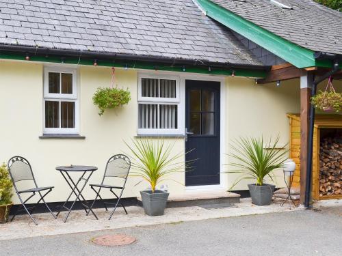 a white house with chairs and a table in front of it at Bluebell in Saint Ewe
