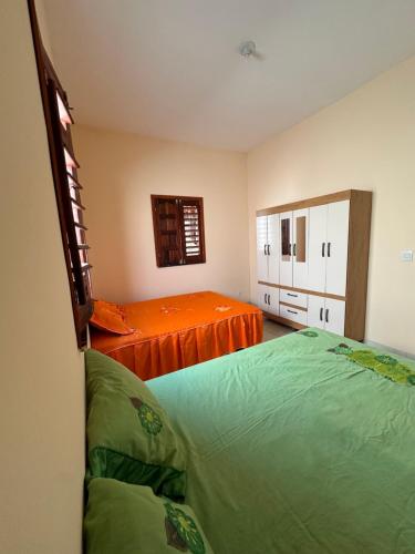 a bedroom with two beds and an orange sheet at Casa Amarela no Fortim in Fortim