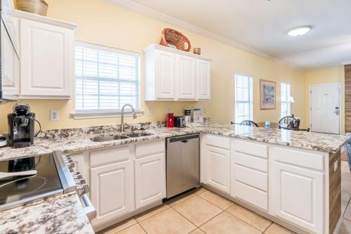 a kitchen with white cabinets and granite counter tops at Orange Beach Villas - Serendipity in Orange Beach