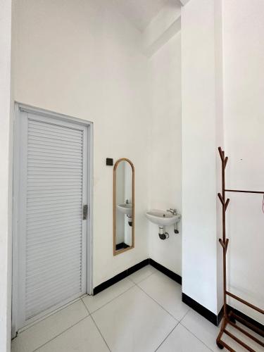 a white bathroom with a sink and a mirror at KeJogja Homestay in Grigak