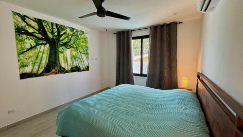 ein Schlafzimmer mit einem Bett und einem Baumgemälde an der Wand in der Unterkunft Casa de Lemon in Coco