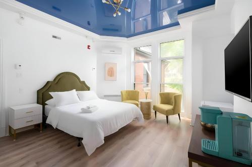 a bedroom with a white bed and a tv at Kozy Stays Penfield - Modern Rooms Heart of downtown in Montréal
