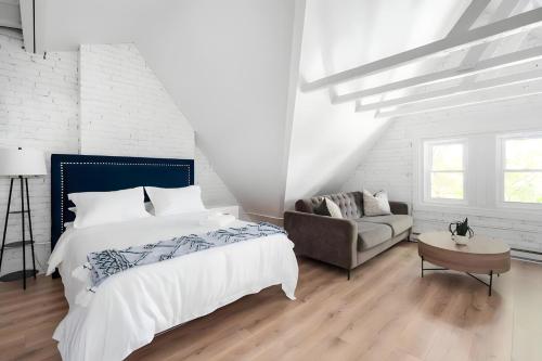 a white bedroom with a bed and a couch at Kozy Stays Penfield - Modern Rooms Heart of downtown in Montréal