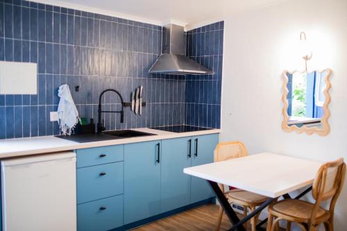 a kitchen with blue cabinets and a white table at Onda - Boutique Garden Ocean View Suite in the Countryside - Vila Pilar in Pilar