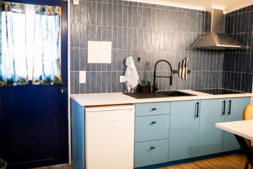 a kitchen with blue and white cabinets and a sink at Onda - Boutique Garden Ocean View Suite in the Countryside - Vila Pilar in Pilar
