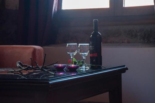 a bottle of wine and two wine glasses on a table at Theasis suites-Ορεινή Φιλοξενία in Kato Trikala Korinthias