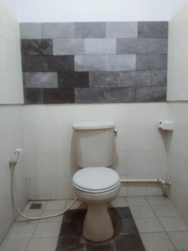 a bathroom with a toilet with a painting on the wall at Efata Homestay in Borobudur