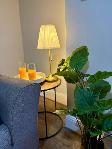 a table with two glasses of orange juice and a lamp at Stylish Southend 4 Bed Sleeps 7 FastWifi Secure Driveway Parking by The Opulent Property Project UK in Southend-on-Sea