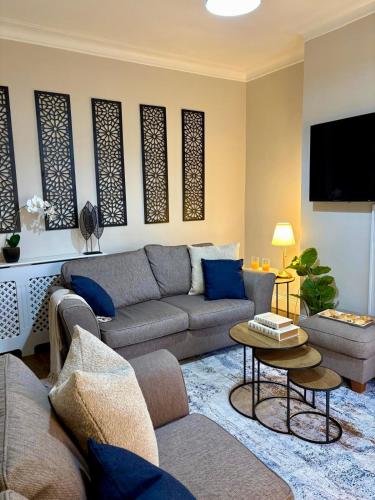 a living room with a couch and a tv at Stylish Southend 4 Bed Sleeps 7 FastWifi Secure Driveway Parking by The Opulent Property Project UK in Southend-on-Sea