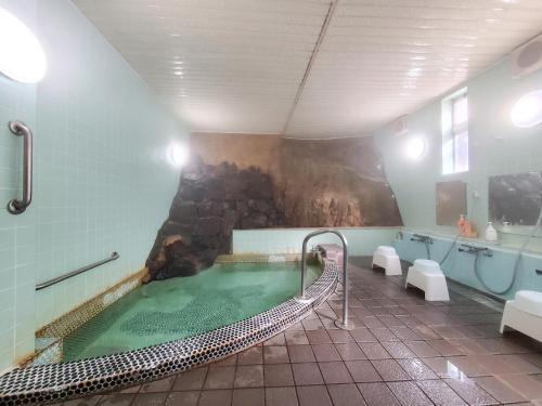 a bathroom with a pool of water in a tub at 偕楽園 in Shirasaka