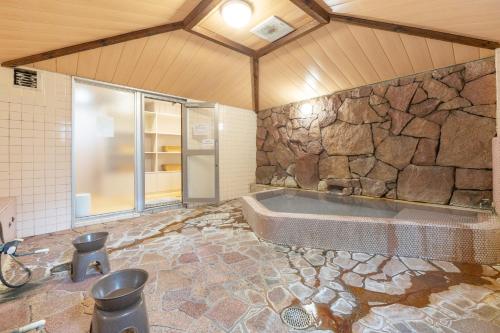 a large bathroom with a tub and a stone wall at Address Nozawa in Nozawa Onsen