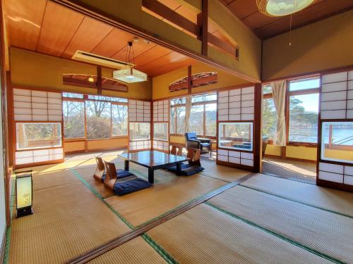 a living room with a table in a room with windows at 偕楽園 in Shirasaka