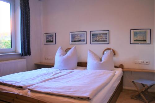 a bedroom with a bed with white sheets and pillows at Lütt Eddy in Kaltenhof