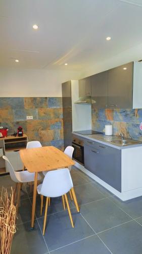 una cucina con un tavolo di legno e sedie bianche di Emma modern suite a Kourou