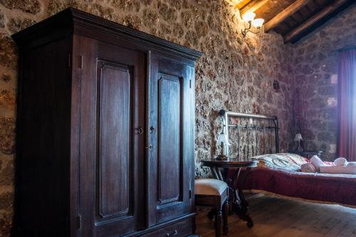 a bedroom with a bed and a wooden cabinet at Theasis suites-Ορεινή Φιλοξενία in Kato Trikala Korinthias