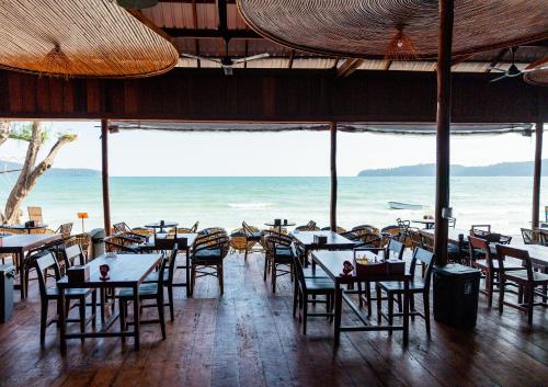 a restaurant with tables and chairs and the ocean at Onederz Koh Rong Sanloem in Koh Rong Sanloem