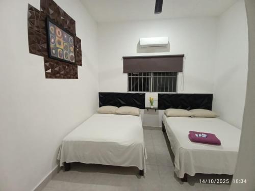 two beds in a room with white walls at Hotel y Hostal AH MUN in Mérida