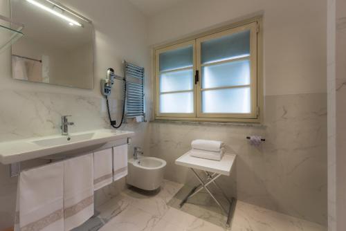 uma casa de banho com um lavatório, um WC e uma janela. em Manuelina Taste Hotel em Recco