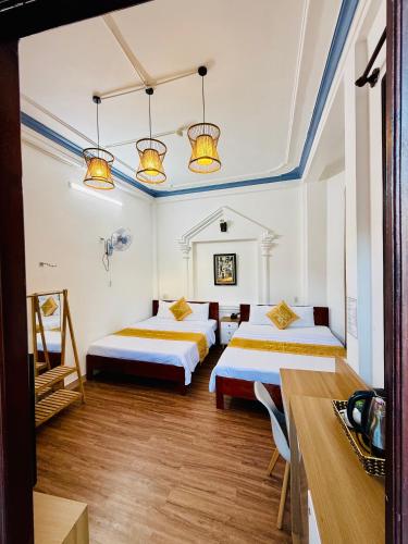 a room with two beds and two tables in it at Eva Homestay in Hue