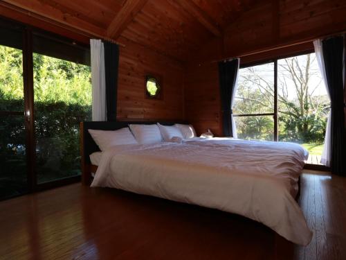 a bedroom with a large bed in a room with windows at La villetta 白浜 in Minamiboso