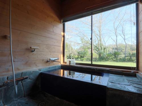 a bathroom with a tub and a large window at La villetta 白浜 in Minamiboso
