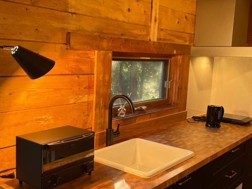 a kitchen counter with a sink and a microwave at A Sleeping Forest in Ito