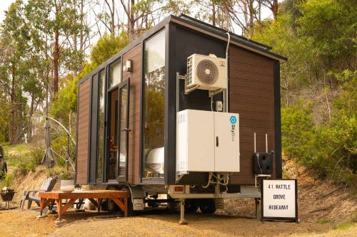 a black tiny house on display with a sign at Wattle Grove Hideaway by Tiny Away in Wattle Grove