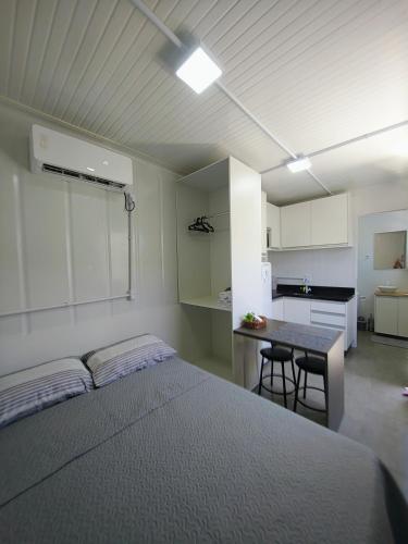 a bedroom with a bed and a table and a kitchen at Loft Navegantes Próximo Aeroporto e BR 101 in Navegantes