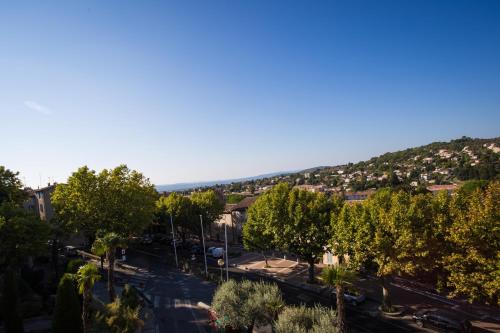 a city street with trees and a hill in the background at Logis hôtel du terreau in Manosque