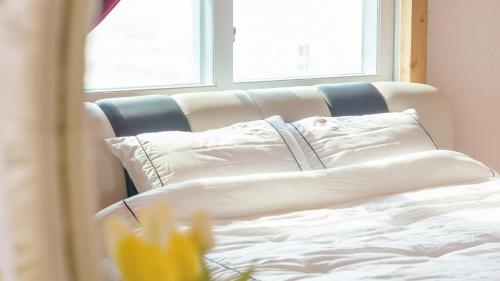 a bed with white sheets and pillows next to a window at Gangwha Jeongwon Pension in Incheon