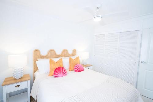 a bedroom with a white bed with pink and orange pillows at The Chelsea Beachside Apartment in The Entrance