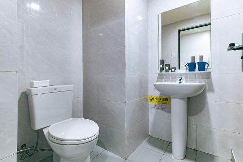 a white bathroom with a toilet and a sink at Luna Hotel Pasay in Manila