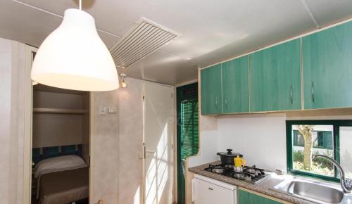 a kitchen with green cabinets and a sink and a light at Happy Village & Camping in La Giustiniana