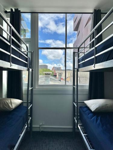 two bunk beds in a room with a window at SpinCity Lodge Auckland in Auckland