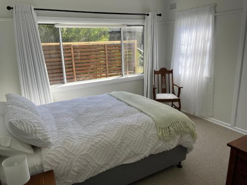a bedroom with a bed and a window and a chair at Moruya Heads Constable Street in Moruya Heads