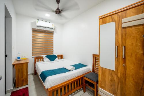 a small bedroom with a bed and a chair at FORA Inn in Cochin