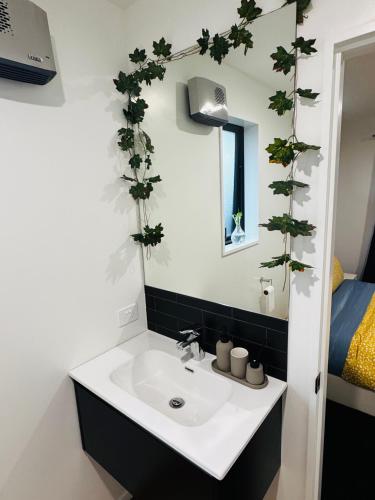 a bathroom with a sink and plants on the wall at Room with en-suite bathroom in Kaiapoi
