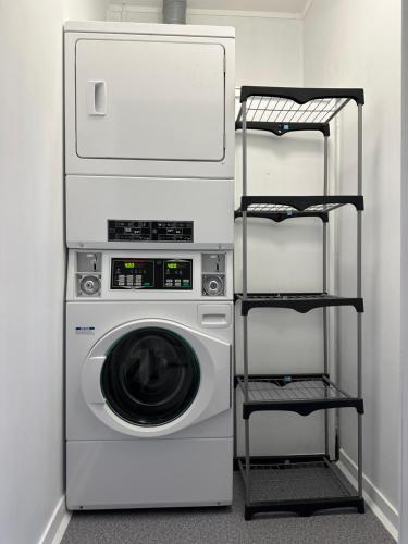 a laundry room with a washing machine and a shelf at SpinCity Lodge Auckland in Auckland