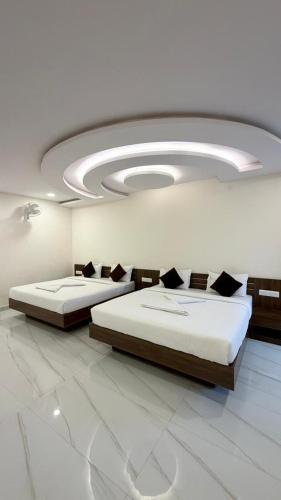 two beds in a large room with a ceiling at SKB Suites in Mysore