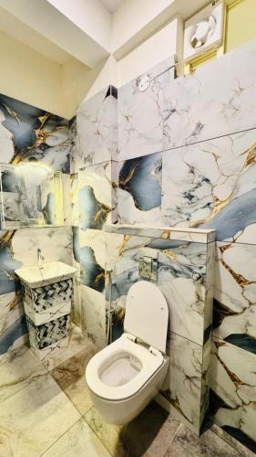 a bathroom with a toilet and a marble wall at SKB Suites in Mysore
