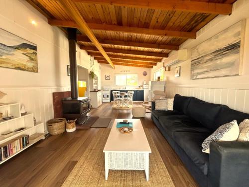 a living room with a black couch and a table at Driftwood Cottage in Dolphin Sands