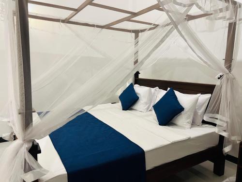 a bed with blue and white pillows in a tent at Sea Breeze Heaven in Tangalle